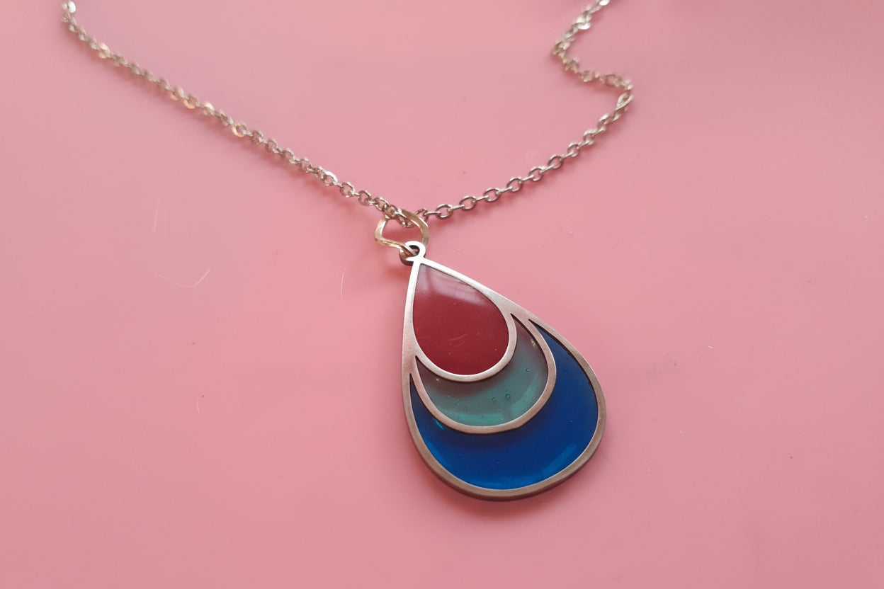 Necklace with a teardrop-shaped pendant on a pink background