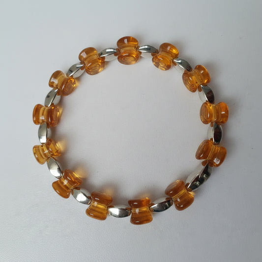 Bracelet with orange and silver beads on a light gray background