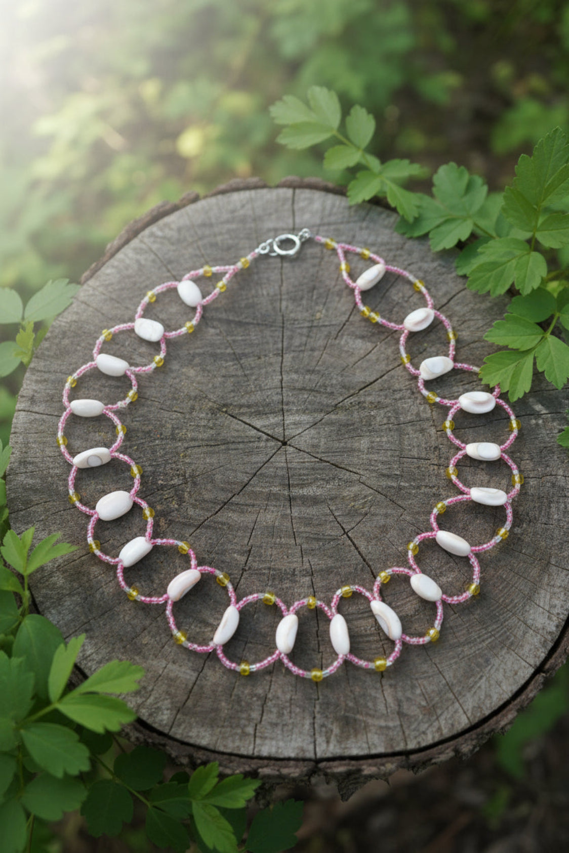 Necklace with shell beads and yellow accents on a white background