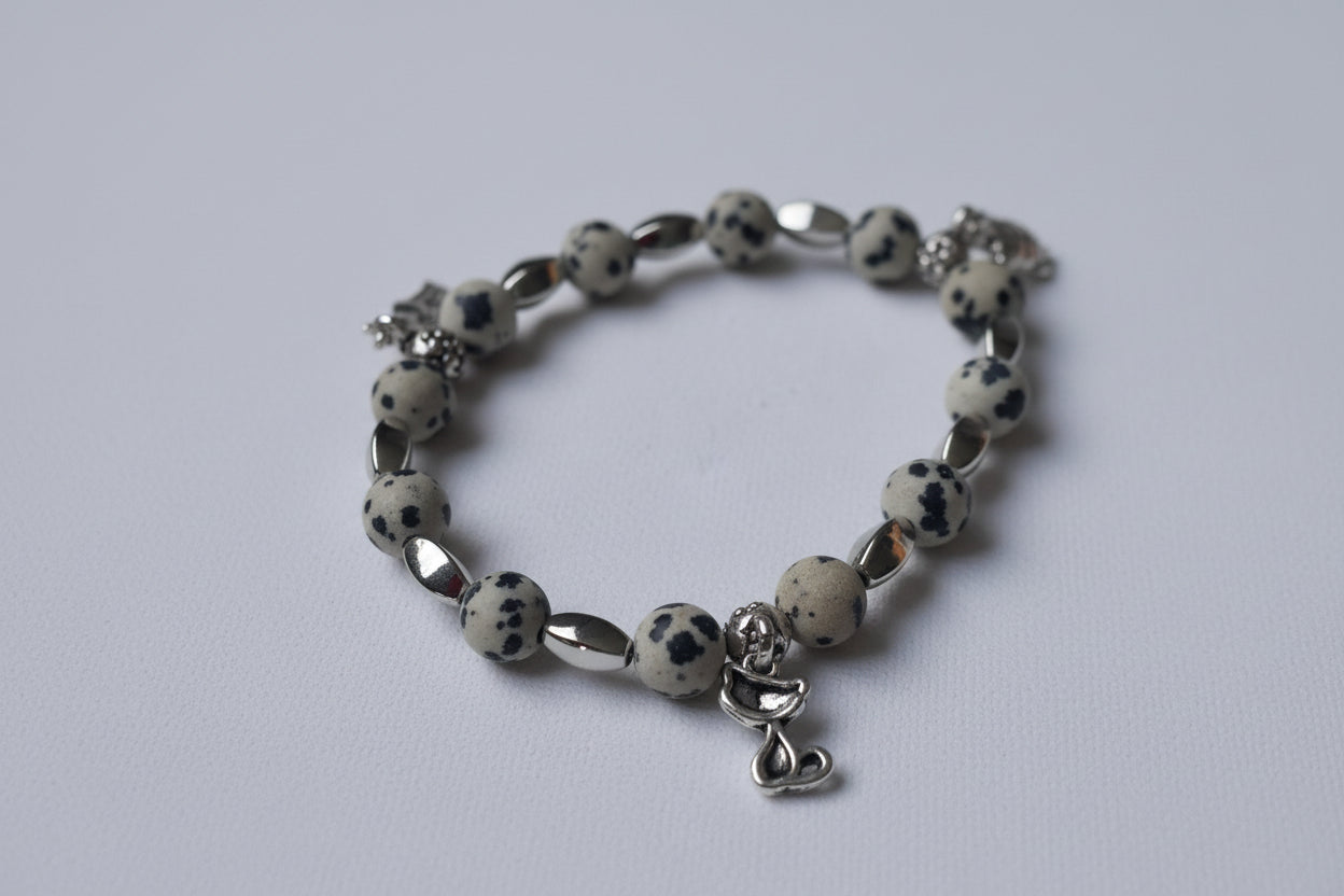 Bracelet with dalmatian Jasper beads and silver charms on a light gray background
