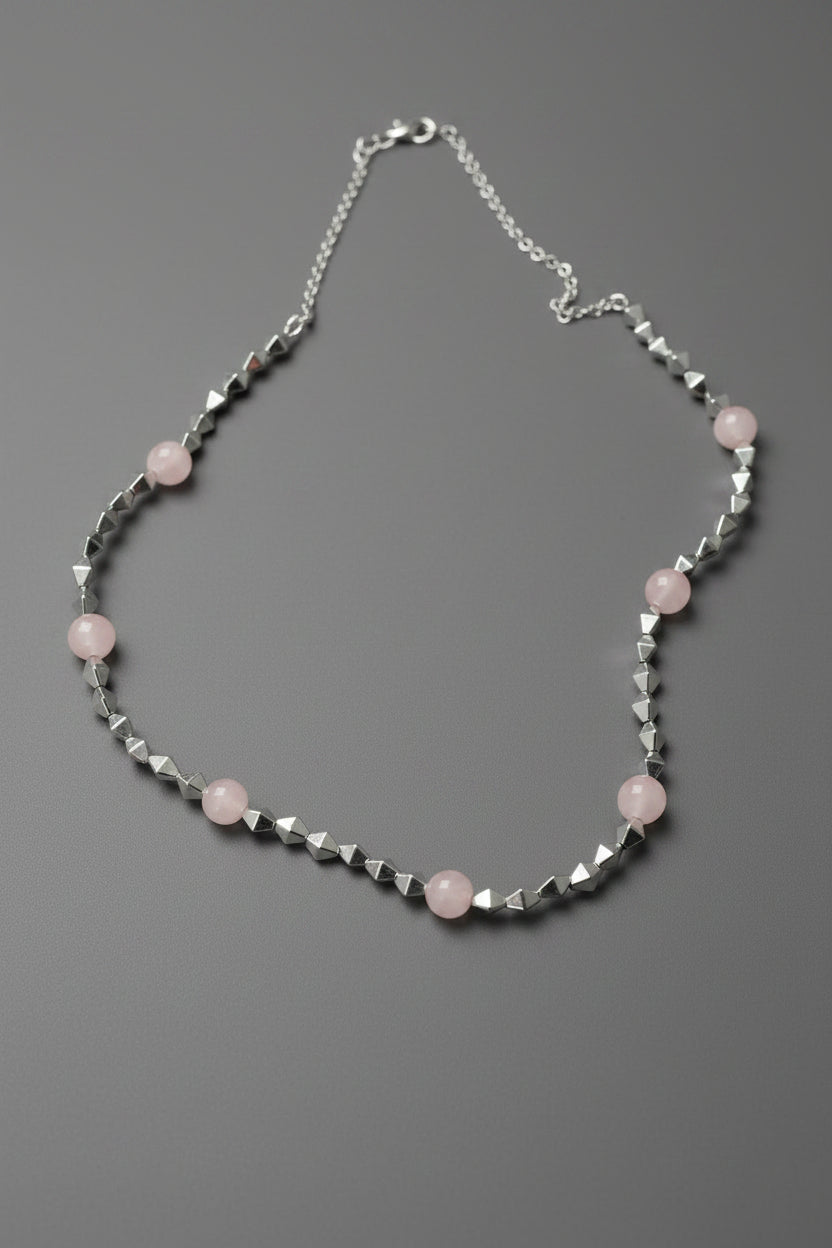 Necklace with pink beads and silver chain on a light gray background
