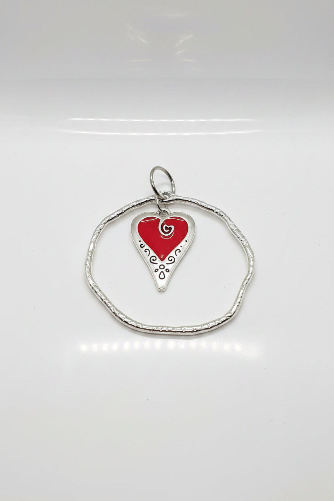 Heart-shaped red pendant on a silver chain against a pink background