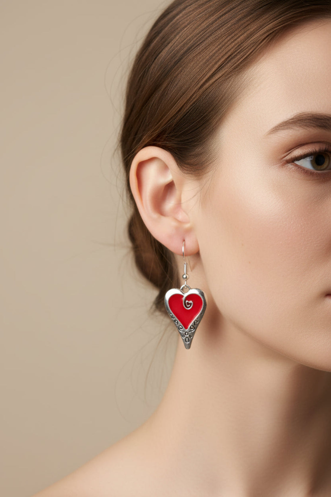 Heart-shaped earrings with red centers and silver borders on a pink background