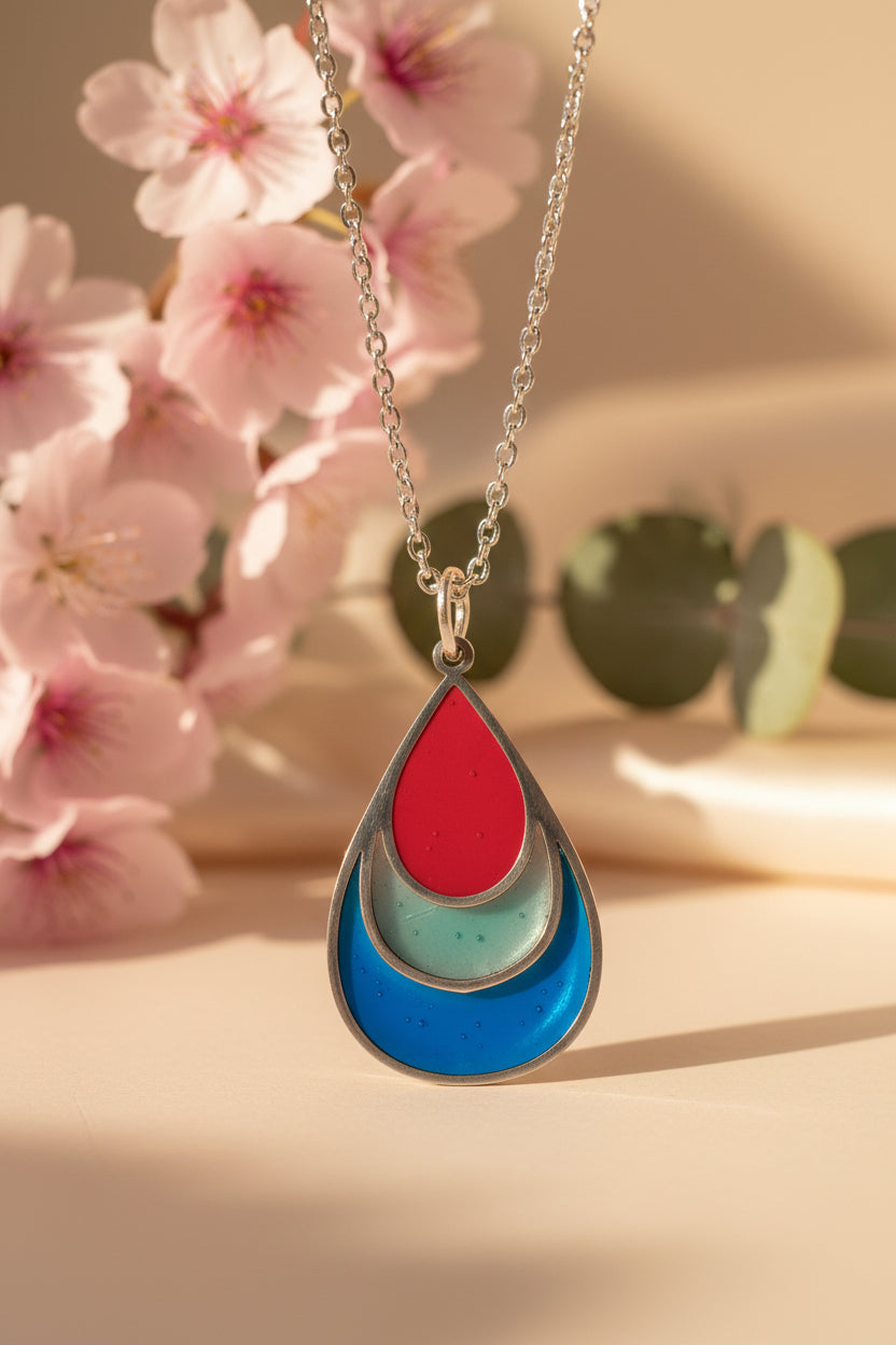 Necklace with a teardrop-shaped pendant on a pink background