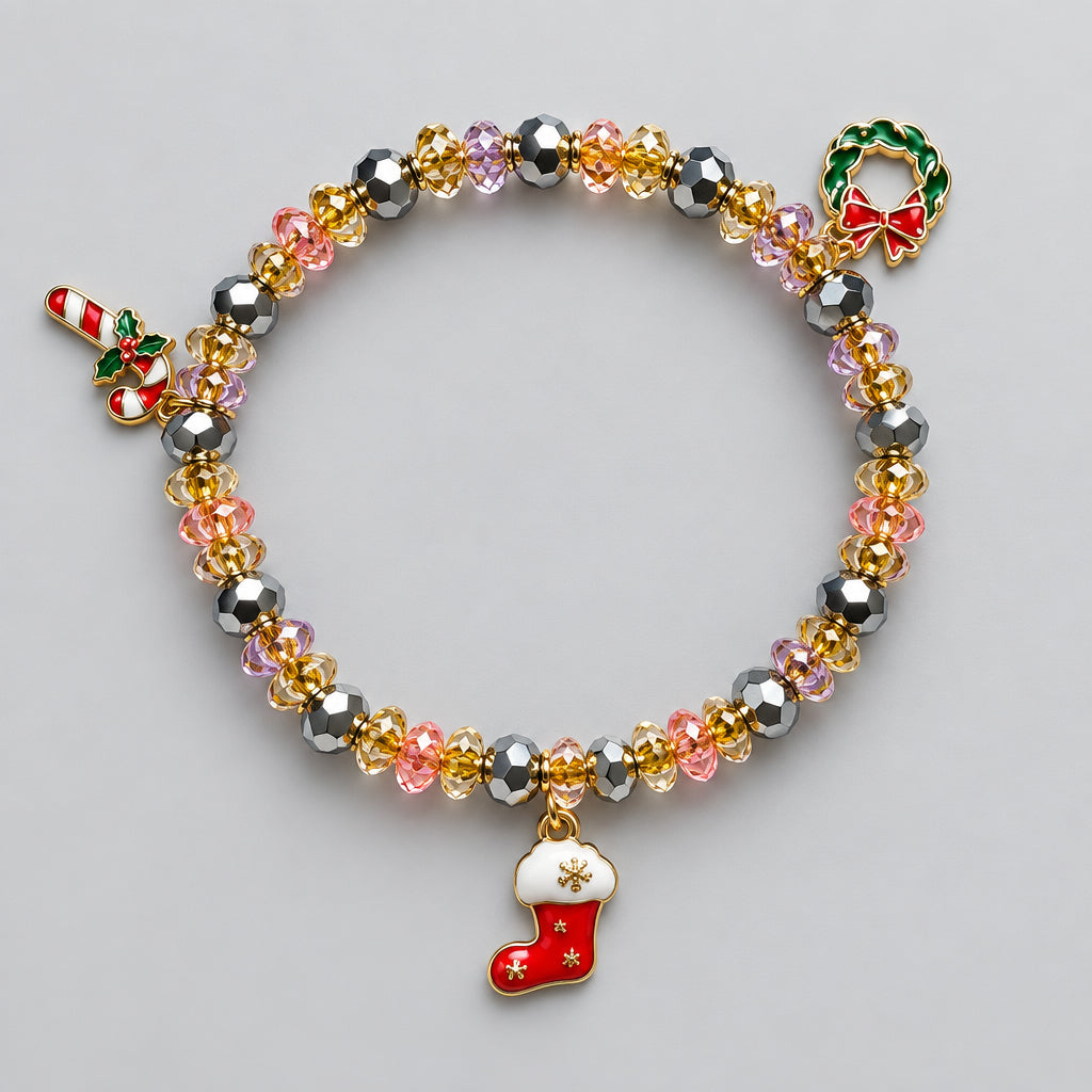 A beaded Christmas-themed bracelet with faceted gold, pink, and gray beads, featuring a gold wreath charm with a red bow, a candy cane charm, and a red and white stocking charm, displayed on a light gray background.