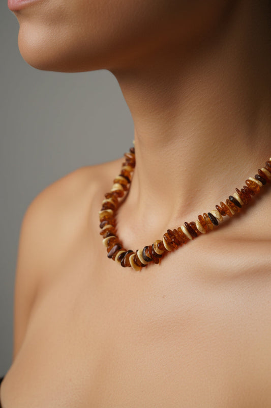 Necklace with brown and gold beads worn by a person against a neutral background