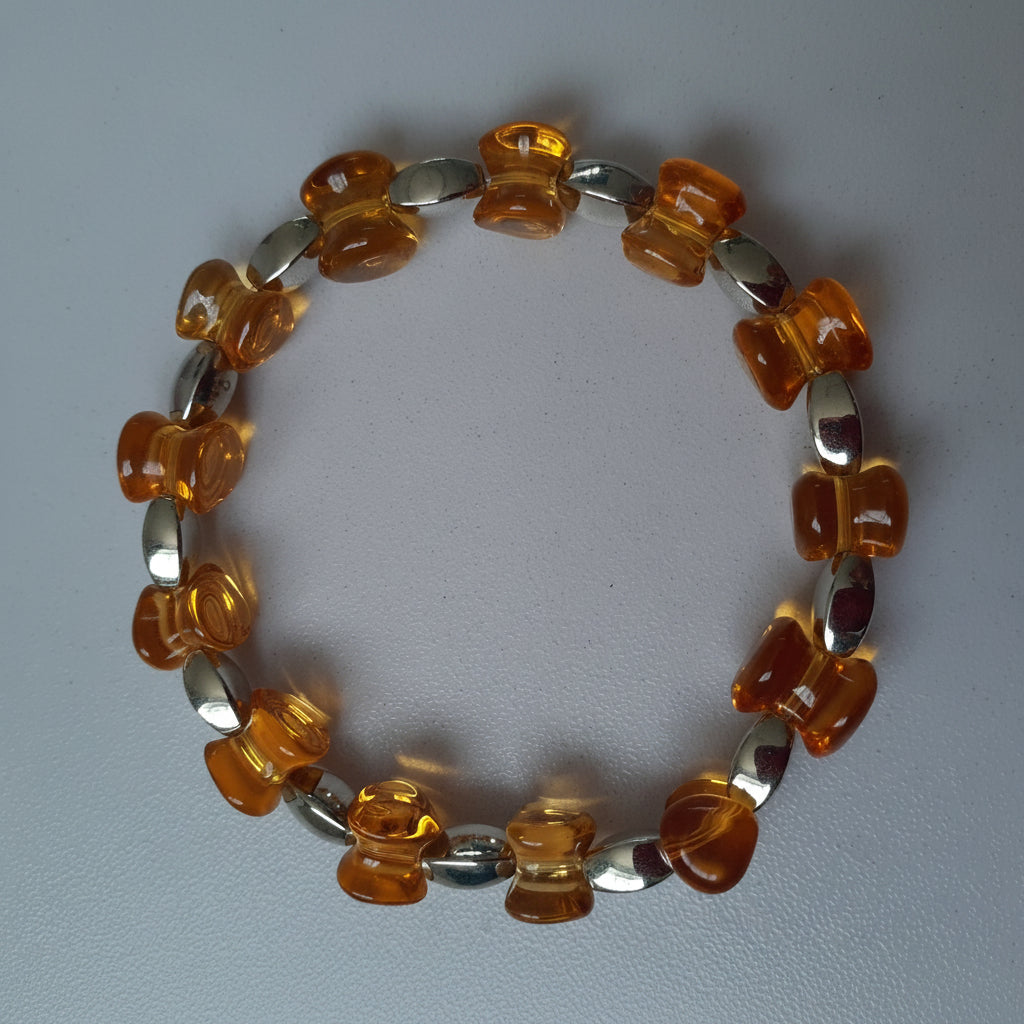 Bracelet with orange and silver beads on a light gray background
