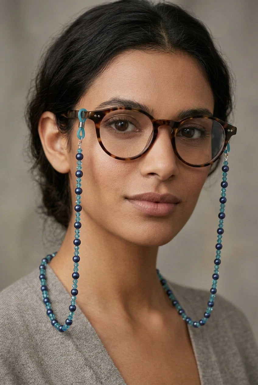 A beaded necklace made of alternating light blue and dark navy blue faceted beads, with silver-toned metal clasps on a plain light gray background.
