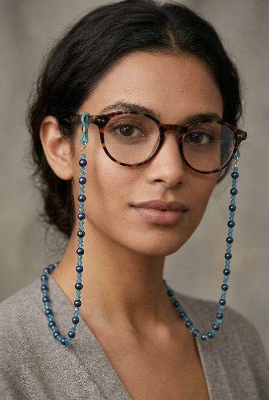 A beaded necklace made of alternating light blue and dark navy blue faceted beads, with silver-toned metal clasps on a plain light gray background.