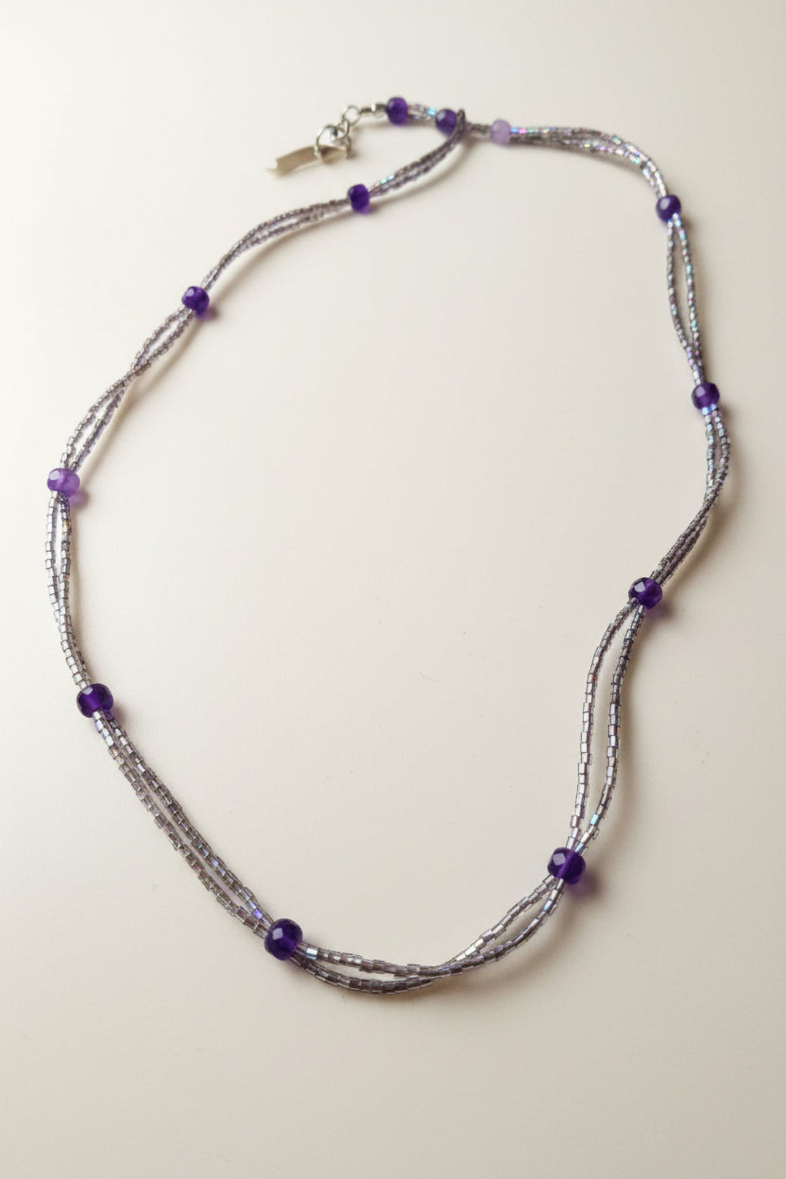 Necklace with amethyst crystals with purple beads on a beige background