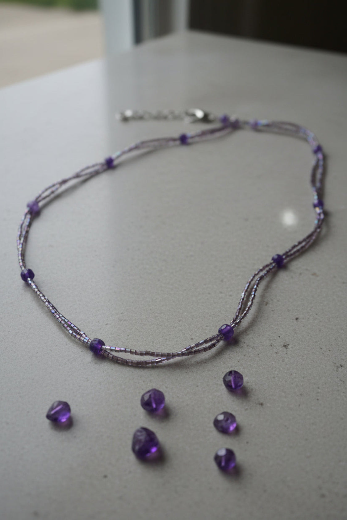 Necklace with amethyst crystals and purple beads on a light surface