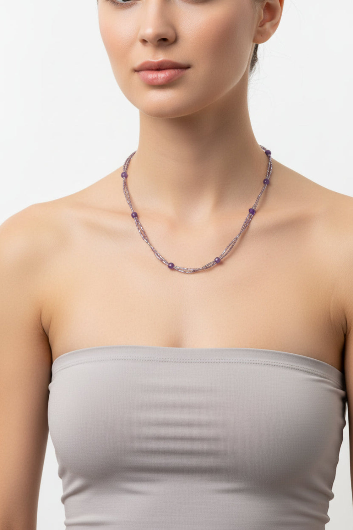 Woman wearing a beaded necklace on a plain background
