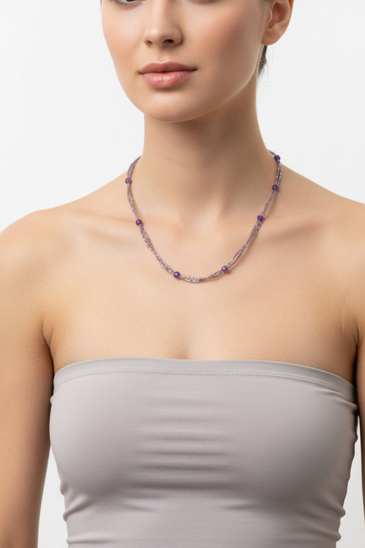 Woman wearing a beaded necklace on a plain background