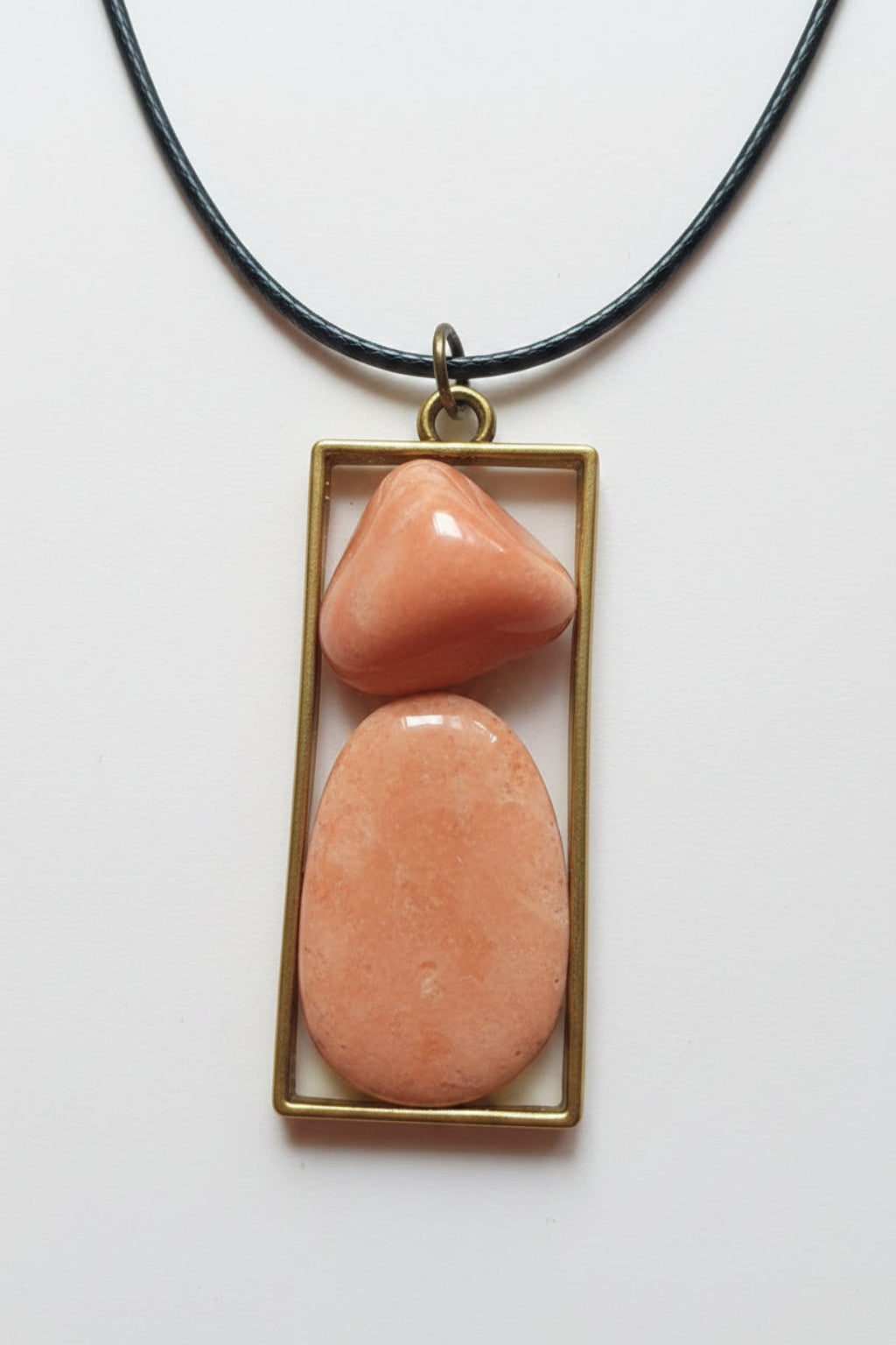 Necklace with a pendant featuring two pink stones in a gold frame on a white background