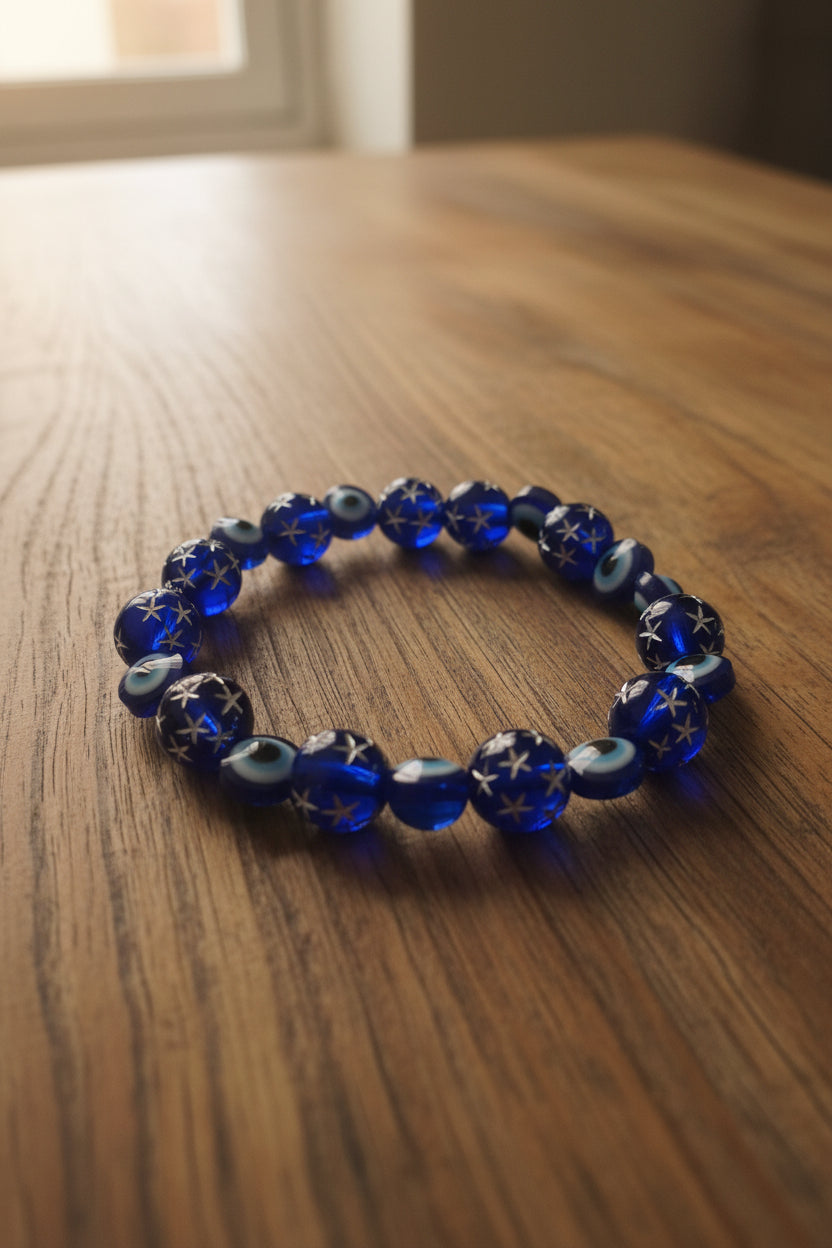 Blue beaded bracelet with star and eye designs on a light gray background