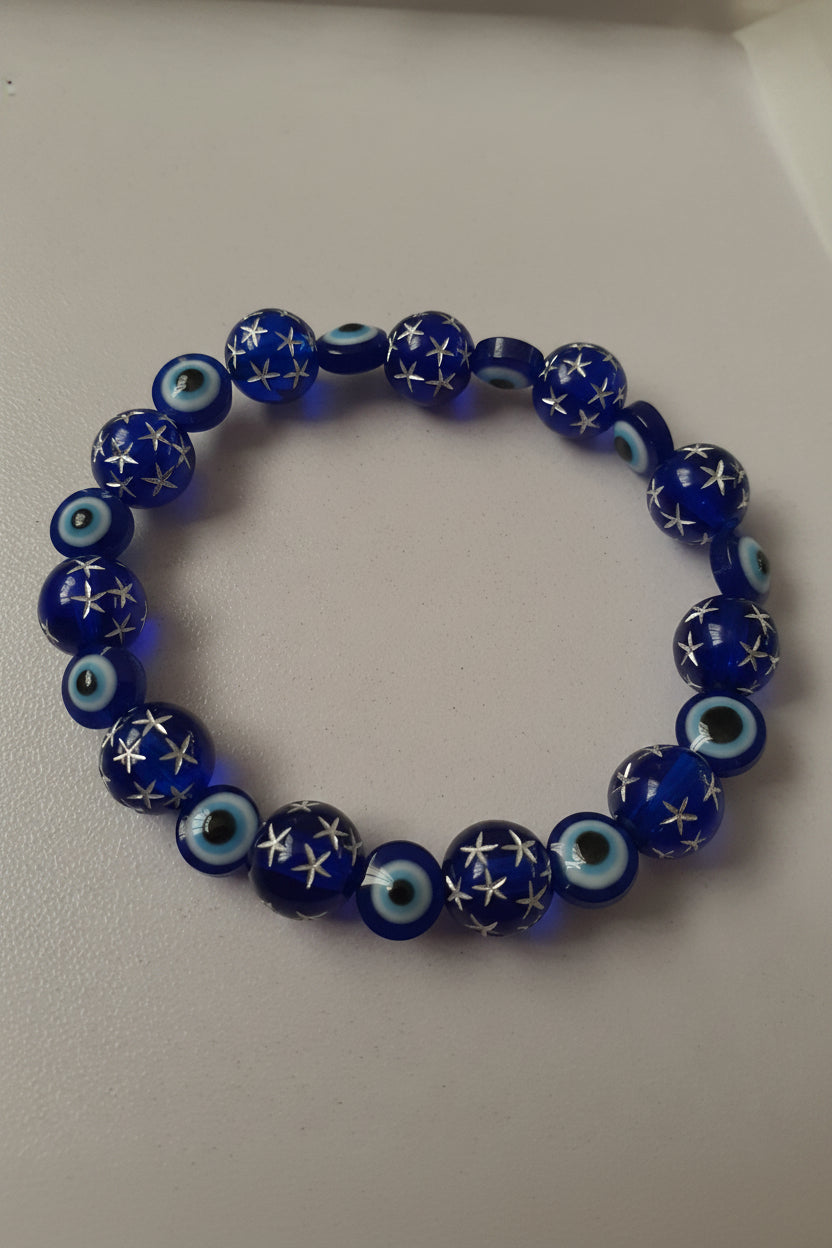 Blue beaded bracelet with star and eye designs on a light gray background