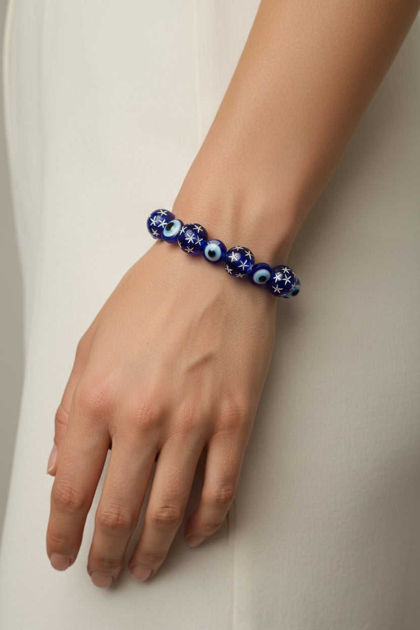 Blue beaded bracelet with star and eye designs on a light gray background