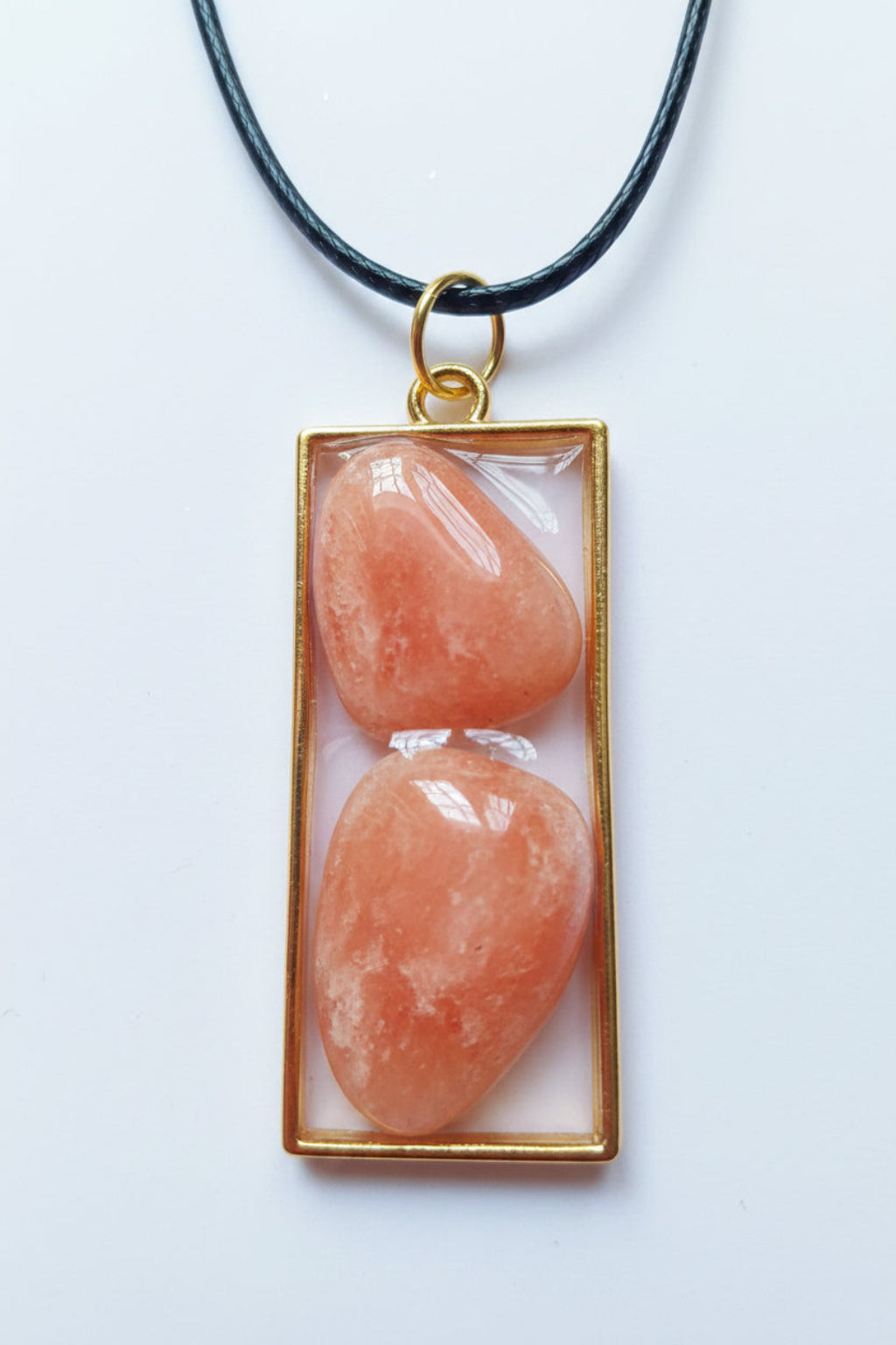 Necklace with a pendant featuring two pink stones in a gold frame on a white background