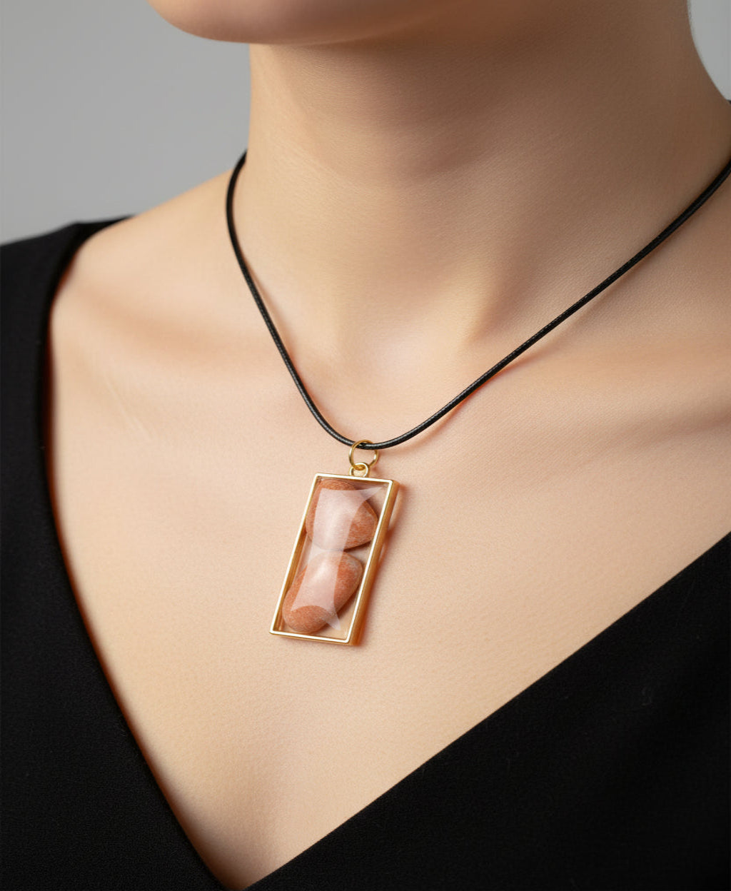 Necklace with a rectangular pendant featuring two stones on a light pink background