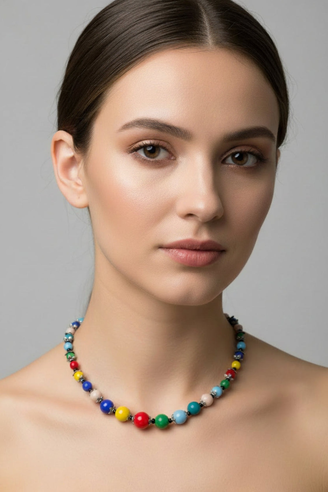 Woman wearing a colorful beaded necklace against a gray background