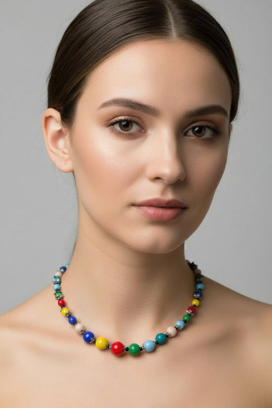 Woman wearing a colorful beaded necklace against a gray background