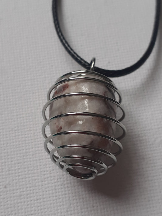 Metallic spiral pendant on a black cord against a light gray background