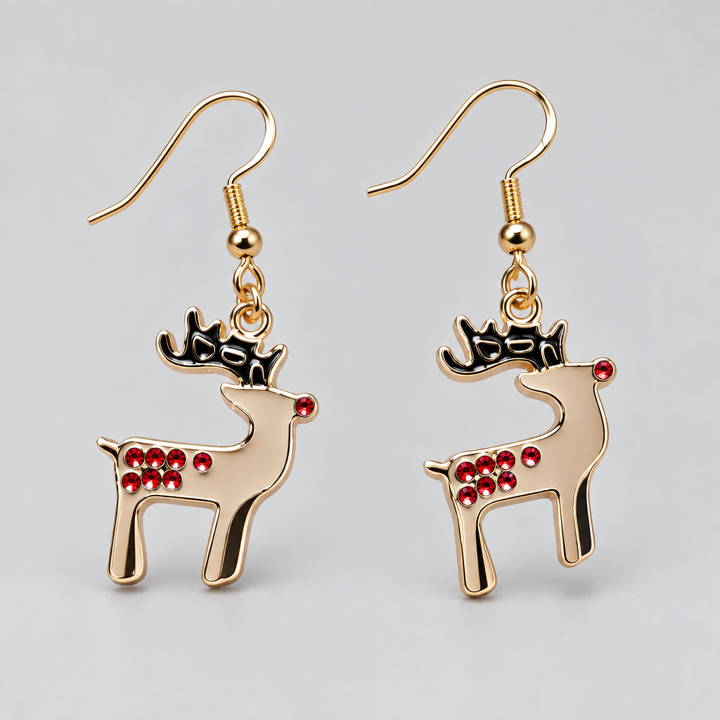 A pair of gold-toned dangle earrings shaped like reindeer, featuring black antlers and red rhinestone spots, displayed on a light pink background.