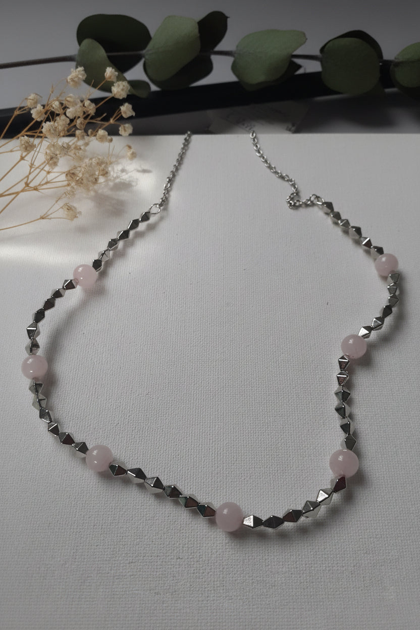 Necklace with pink beads and silver chain on a light gray background