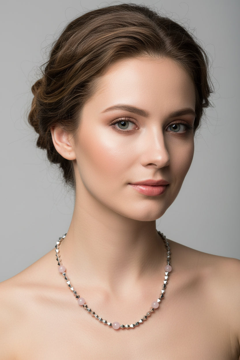 Necklace with pink beads and silver chain on a light gray background