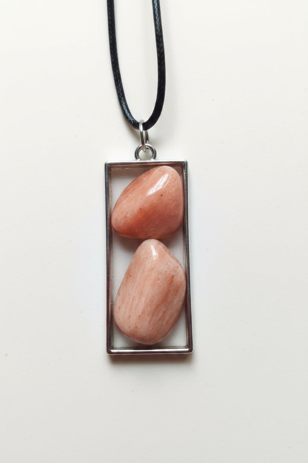 Rectangular pendant with two stones on a pink background