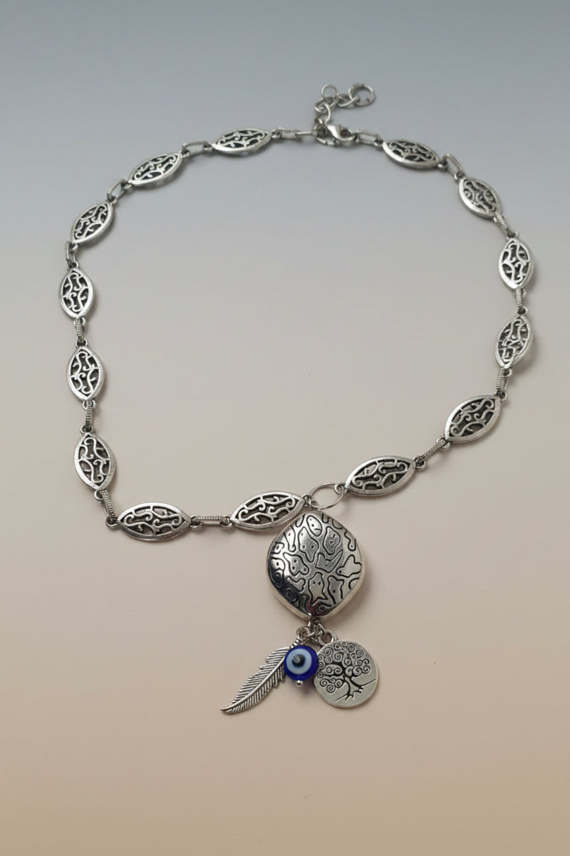 Silver tone necklace with decorative elements on a gray background