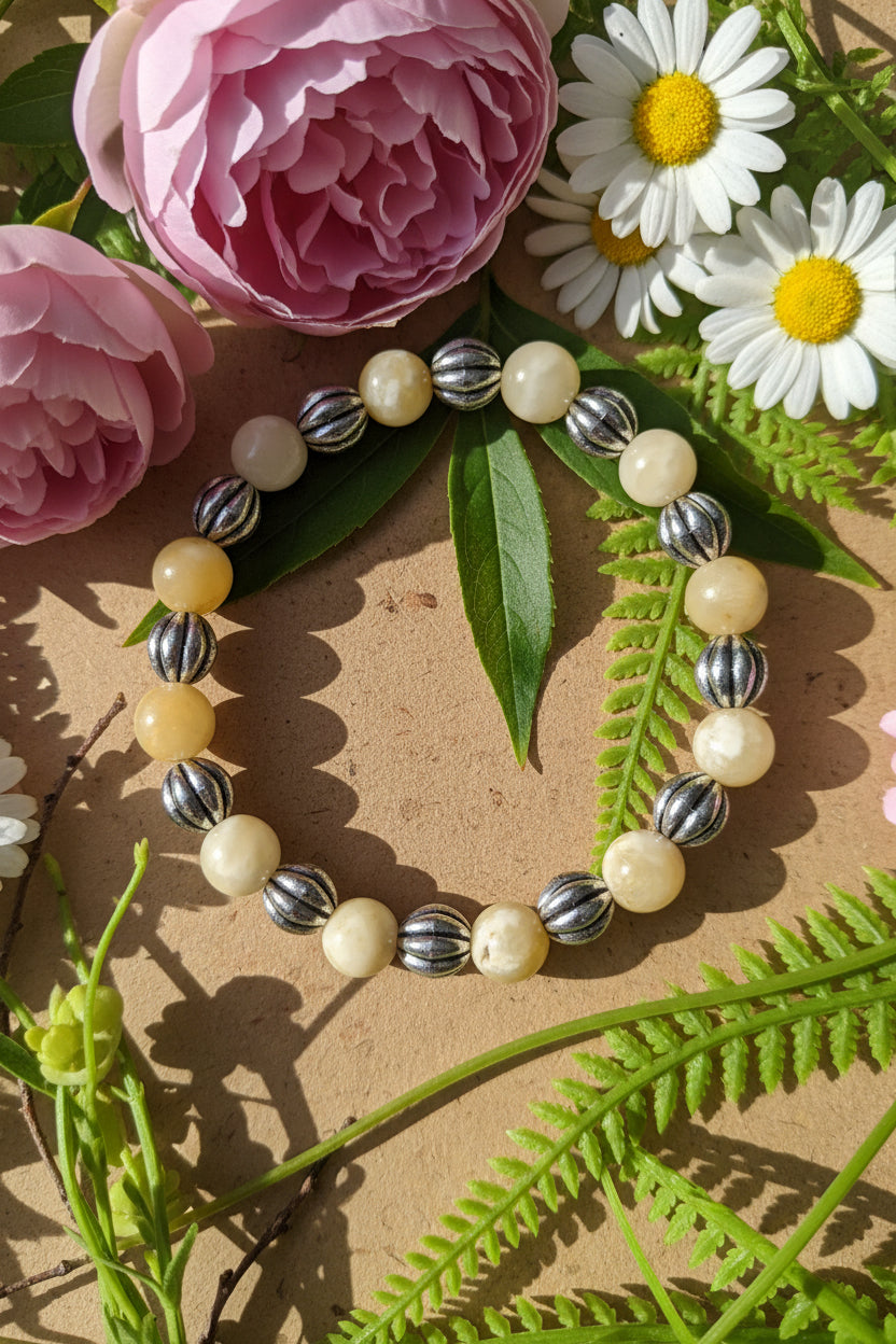Bracelet with pearls and silver beads on a background of pink flowers and green leaves