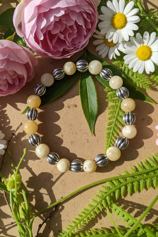 Bracelet with pearls and silver beads on a background of pink flowers and green leaves