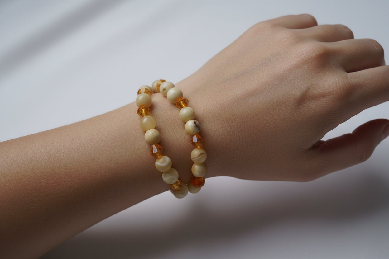 Hand wearing a beaded bracelet on a plain background