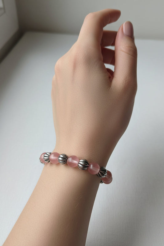 Hand wearing a pink beaded bracelet on a light background