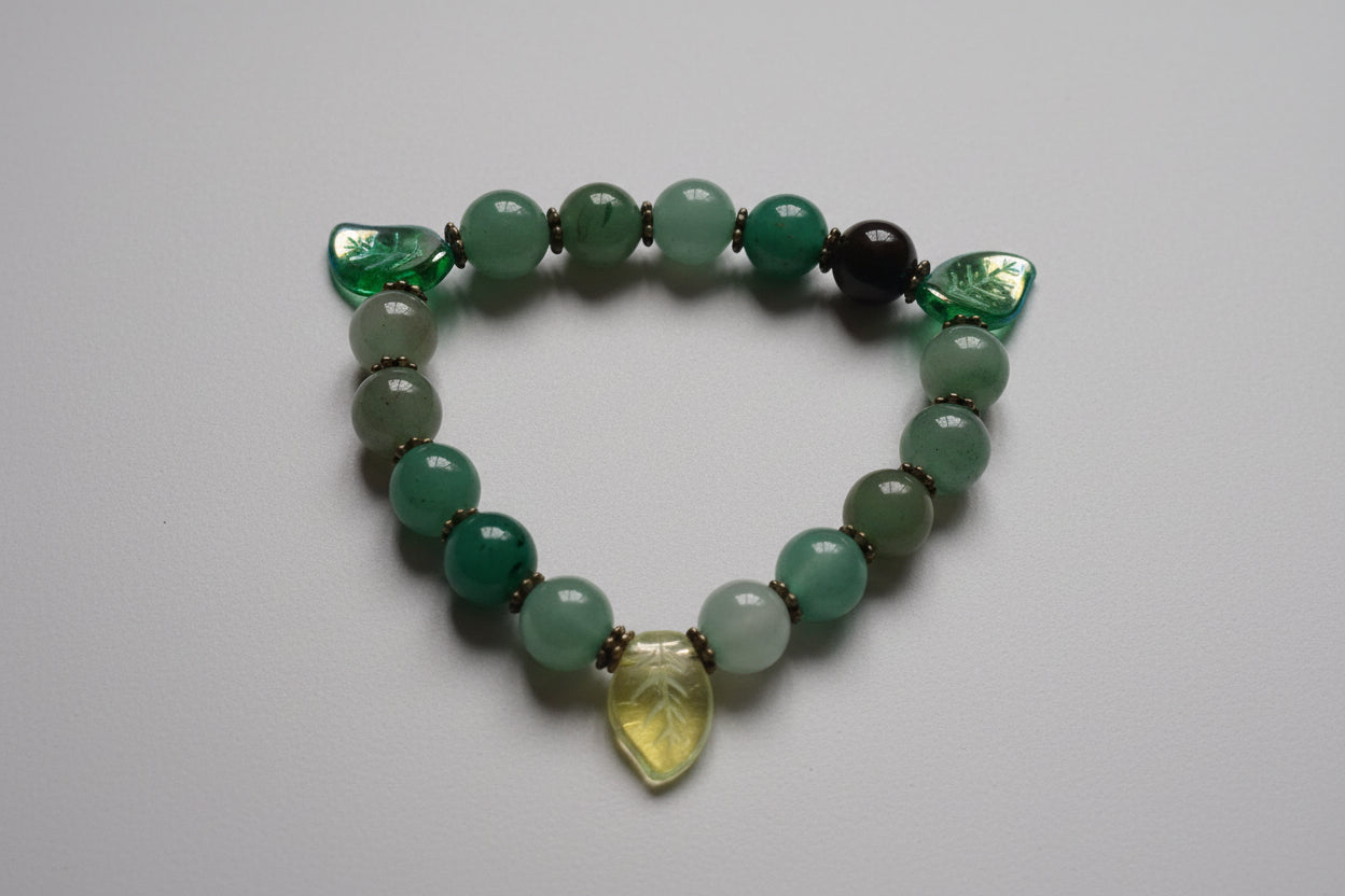 Green beaded bracelet with a heart-shaped charm on a light gray background